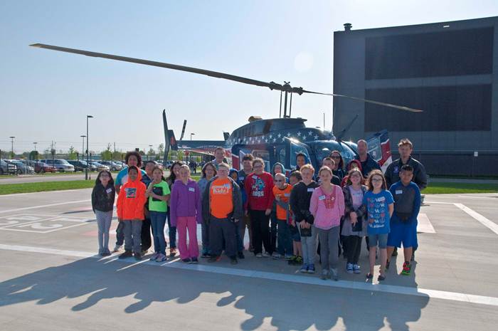 group of children in front of a helicopter src=